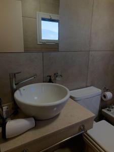 a bathroom with a sink and a toilet and a mirror at Villa Ober Suites in Neuquén
