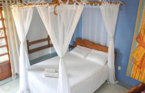 a bedroom with a bed with white curtains at Casa Sol Nascente in Itacaré