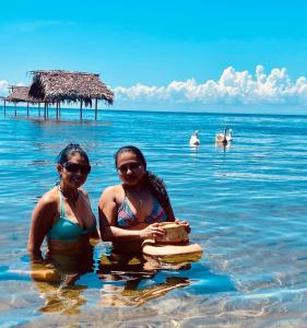two women standing in the water in the ocean at Hotel La Casa Rosada in Lívingston