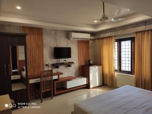 a bedroom with a bed and a desk and a television at Hotel Sree Gokulam Apartments in Guruvāyūr