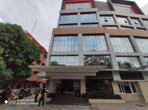 un edificio alto con gente parada frente a él en Hotel Sree Gokulam Apartments en Guruvāyūr