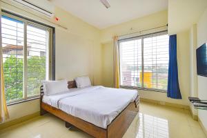 a bedroom with a bed and two large windows at FabExpress Golden Leaf Airport in Pune