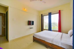 a bedroom with a bed and a window at FabExpress Golden Leaf Airport in Pune