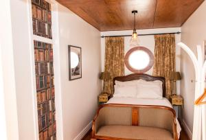 CartertonThe Alchemist Retreat, Private Studio in Carterton的一间卧室设有床铺和窗户,备有书籍