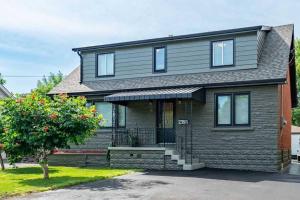 een grijs huis met een veranda en een boom bij Tastefully decorated spacious apartment Burlington in Burlington +22 foto's