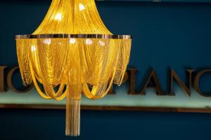 a gold chandelier with a sign in the background at Hotel Piano in Szeged