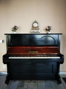 a black piano with a clock on top of it at Hotel Unirea in Focşani