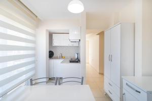 a kitchen with white counters and chairs in a room at Apartments Near to City Center and Beach in Marmaris
