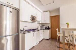eine kleine Küche mit weißen Schränken und einer Mikrowelle in der Unterkunft Precioso apartamento nuevo en el centro de A Coruña! in A Coruña + 11 Fotos
