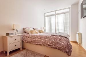 a white bedroom with a bed with a window at Precioso apartamento nuevo en el centro de A Coruña! in A Coruña