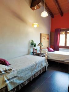 a bedroom with two beds in a room with red walls at En Huerto de Catalina in Fuentes de Béjar