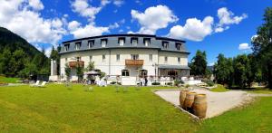 a large white building with a lawn in front of it at Hotel Saisera in Valbruna