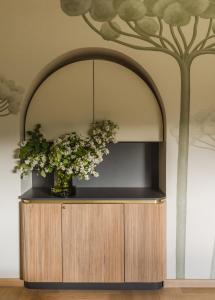 a vase of flowers on a cabinet with a tree on the wall at Dziki Dom in Wetlina
