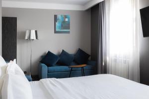 モスクワにあるHartwell Hotel Москва Маяковскаяのベッドルーム(ベッド1台、青いソファ付)