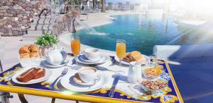 a table with breakfast food and drinks next to a pool at Hotel Myage in Ischia