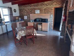a kitchen with a table and chairs and a brick wall at White Rose Guest House in Vanderbijlpark