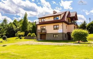 a house on a hill with a green lawn at Apartamenty Pod Jaworzem in Ptaszkowa