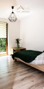 Apartamenty Pod Jaworzem في Ptaszkowa: غرفة نوم بسرير كبير مع بطانية خضراء