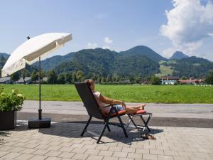 a woman sitting in a chair under an umbrella at Glühwürmchen Cottage in Oberaudorf +9 photos