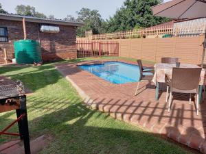 a backyard with a pool and a table and chairs at White Rose Guest House in Vanderbijlpark