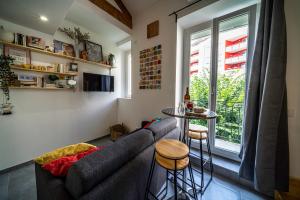 sala de estar con sofá, mesa y ventana en Le Pop'Art - Rent4night Grenoble, en Grenoble