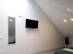 a flat screen tv on the wall of a bedroom at Kambarių nuoma - Pašakarniai SAURIDA in Akmenė