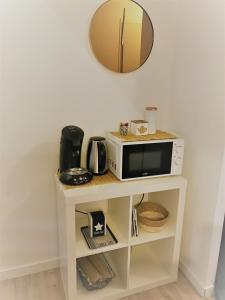 a microwave on a shelf with a mirror at "Studiocaroline44", entre la ville et la mer, Parking, Wifi, terrasse privé, cuisine, moins de 15min aéroport in Bouaye