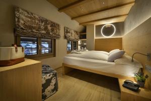 1 dormitorio con 1 cama blanca grande y ventanas en Hotel Compagnoni, en Livigno