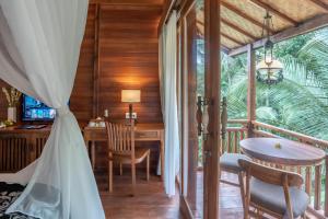 a room with a desk and a table and chairs at The Compass Rose Ubud in Ubud