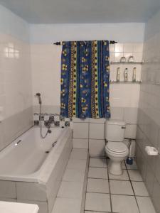 een badkamer met een bad, een toilet en een douchegordijn bij Oupie-se-Plekkie in Velddrif