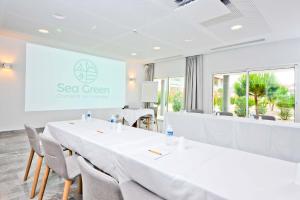 a conference room with white tables and chairs and a screen at Hôtel Les Grenettes in Sainte-Marie-de-Ré