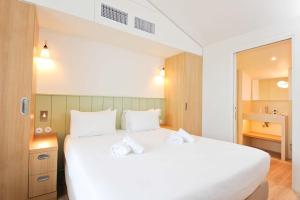 a bedroom with a large bed with white sheets at Hôtel Les Grenettes in Sainte-Marie-de-Ré