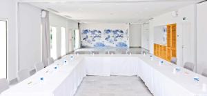 a large white room with white tables and chairs at Hôtel Les Grenettes in Sainte-Marie-de-Ré