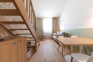 a living room with a wooden table and a staircase at Hôtel Les Grenettes in Sainte-Marie-de-Ré