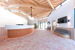 a large lobby with a reception desk and a couch at Hôtel Les Grenettes in Sainte-Marie-de-Ré