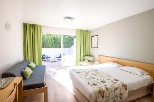a bedroom with a bed and a couch and a window at Hôtel Les Grenettes in Sainte-Marie-de-Ré
