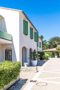a white building with green shutters on it at Hôtel Les Grenettes in Sainte-Marie-de-Ré