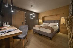 Hotel Compagnoni في ليفينو: غرفة نوم بسرير ومكتب وكرسي