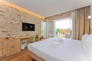 a hotel room with a large bed and a tv at Hôtel Les Grenettes in Sainte-Marie-de-Ré