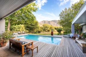 a swimming pool on a wooden deck with a view of the mountains at In Abundance Guest House in Montagu