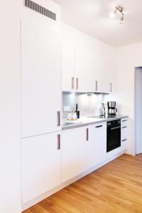cocina blanca con armarios blancos y suelo de madera en New, quiet flat next to U1, VIC, shopping mall,..., en Viena