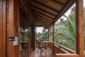 un balcón de una casa con mesas y sillas en The Compass Rose Ubud, en Ubud