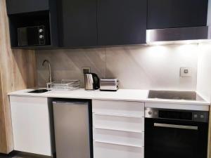 a kitchen with black cabinets and a white counter top at Menlyn Residence - Luxury Studio Apartment in Pretoria