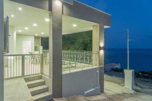 a house with a balcony with a view of the ocean at Tzortzi's Family Apartments in Kaloi Limenes