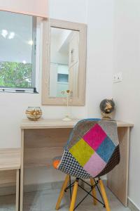 a chair with a colorful blanket on it next to a desk at Tzortzi's Family Apartments in Kaloi Limenes