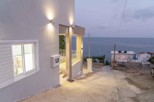 a house with a balcony with a view of the ocean at Tzortzi's Family Apartments in Kaloi Limenes
