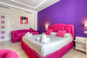 a pink bedroom with a large bed and a couch at Tiffany Suites in Sorrento