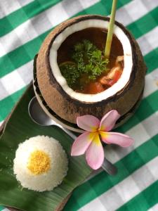 a bowl of soup with rice and a flower on a plate at Arco Iris Boutique Hotel & Restaurant in Candidasa