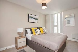 um quarto com uma cama com almofadas amarelas em Lovely Apartment - Private Parking - Stadium Views em Manchester
