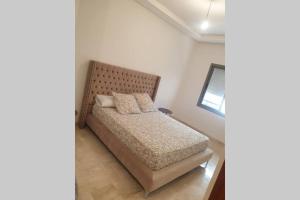 a bedroom with a bed with a wooden headboard at Apartment Near & close to Casablanca Mohammed V International Airport in Nouaseur